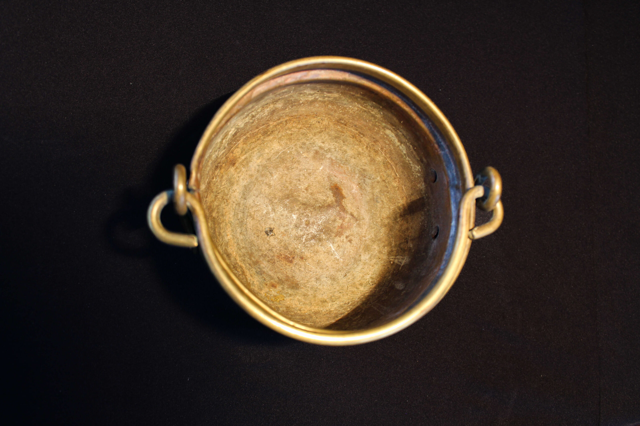 1900’lü yılların başlarına tarihlenen bu pirinçten yapılmış küçük kova, yaklaşık 500 ml hacmiyle dönemin gündelik yaşamında kullanılan işlevsel bir parçadır. sade ama zarif formu, hem kullanım amacını hem de dönemin el işçiliğini yansıtır. küçük su kovaları, özellikle mutfaklarda, sofralarda ya da temizlik sırasında pratik bir yardımcı olarak tercih edilirdi. bugün ise hem dekoratif bir obje hem de nostaljik bir hatıra niteliği taşıyan bu pirinç kova, geçmişin gündelik ritüellerini ve 20. yüzyıl başlarının yaşam kültürünü günümüze taşır. 1900’lü yılların başlarına tarihlenen bu pirinçten yapılmış küçük kova, yaklaşık 500 ml hacmiyle dönemin gündelik yaşamında kullanılan işlevsel bir parçadır. sade ama zarif formu, hem kullanım amacını hem de dönemin el işçiliğini yansıtır. küçük su kovaları, özellikle mutfaklarda, sofralarda ya da temizlik sırasında pratik bir yardımcı olarak tercih edilirdi. bugün ise hem dekoratif bir obje hem de nostaljik bir hatıra niteliği taşıyan bu pirinç kova, geçmişin gündelik ritüellerini ve 20. yüzyıl başlarının yaşam kültürünü günümüze taşır.